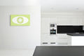 Modern kitchen with white cabinets, black  countertop and backsplash, and a green and white abstract artwork on the wall.